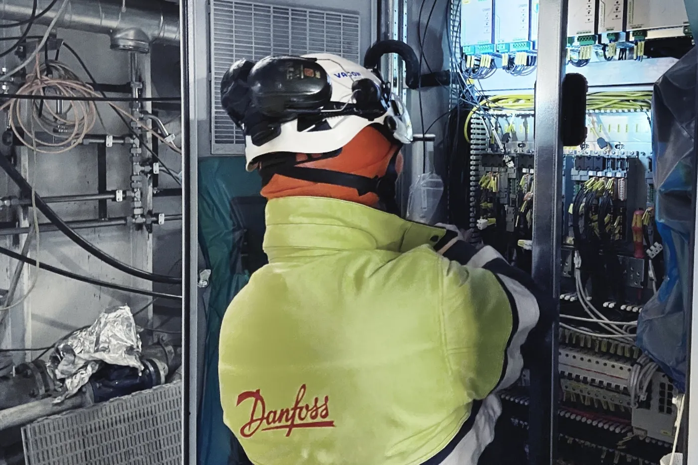 Técnico con casco revisando los gabinetes de variadores en la sala de máquinas de un ferry